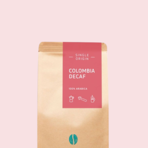 Kaffeepackung aus Packpapier mit pinkem Etikett für den Colombia Decaf Single Origin und den Worten 100% Arabica, darunter Symbole für Herdkanne, Siebträger und French Press. Unter dem Etikett das aufgestempelte Blaue Bohne Rösterei-Logo.
