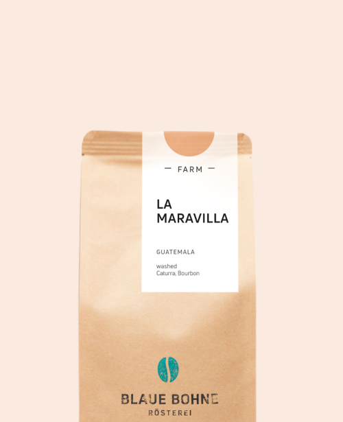 Kaffeepackung aus Packpapier weißem Etikett und leicht Orange oben für den La Maravilla Single Origin und den Worten - Farm - La Maravilla, Guatemala, Washed, Caturra, Bourbon. Unter dem Etikett das aufgestempelte Blaue Bohne Rösterei-Logo.