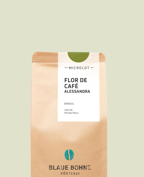 Kaffeepackung aus Packpapier mit weißem Etikett und grünem Kreis oben für den Microlot Flor de Café - Alessandra Single Origin und den Worten Brasilien sowie Natural, Mundo Novo. Unter dem Etikett das aufgestempelte Blaue Bohne Rösterei-Logo.