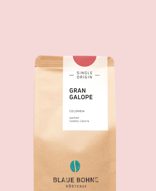 Kaffeepackung aus Packpapier weißem Etikett und Dunkle Pink oben für den Gran Galope Single Origin und den Worten - Single Origin - Gran Galope, Colombia, Washed, Castillo, Caturra. Unter dem Etikett das aufgestempelte Blaue Bohne Rösterei-Logo.