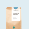 Kaffeepackung aus Packpapier mit weißem Etikett und hellblauem Bogen oben für den El Puente Anaeróbico Microlot Single Origin mit den Worten - El Puente, Honduras, Anaerobic Natural, Red Catuai. Unter dem Etikett das aufgestempelte Blaue Bohne Rösterei-Logo.