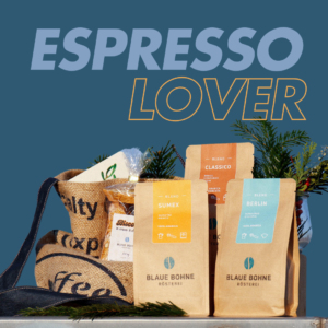 Eine lebendige Präsentation des Espresso Lover X-mas Coffee Sets von Blaue Bohne mit den Blends Berlin, Classico und Sumex. Dazu eine Packung Biscotti, eine handgemachte Weihnachtskarte und eine upgecycelte Kaffeesack-Tasche mit festlichem Tannengrün.